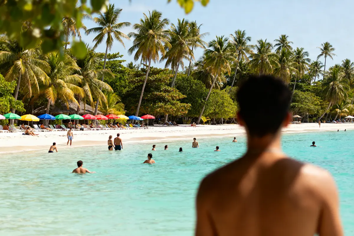Plage tropicale avec palmiers et parasols, idéale pour décider où aller au soleil en décembre
